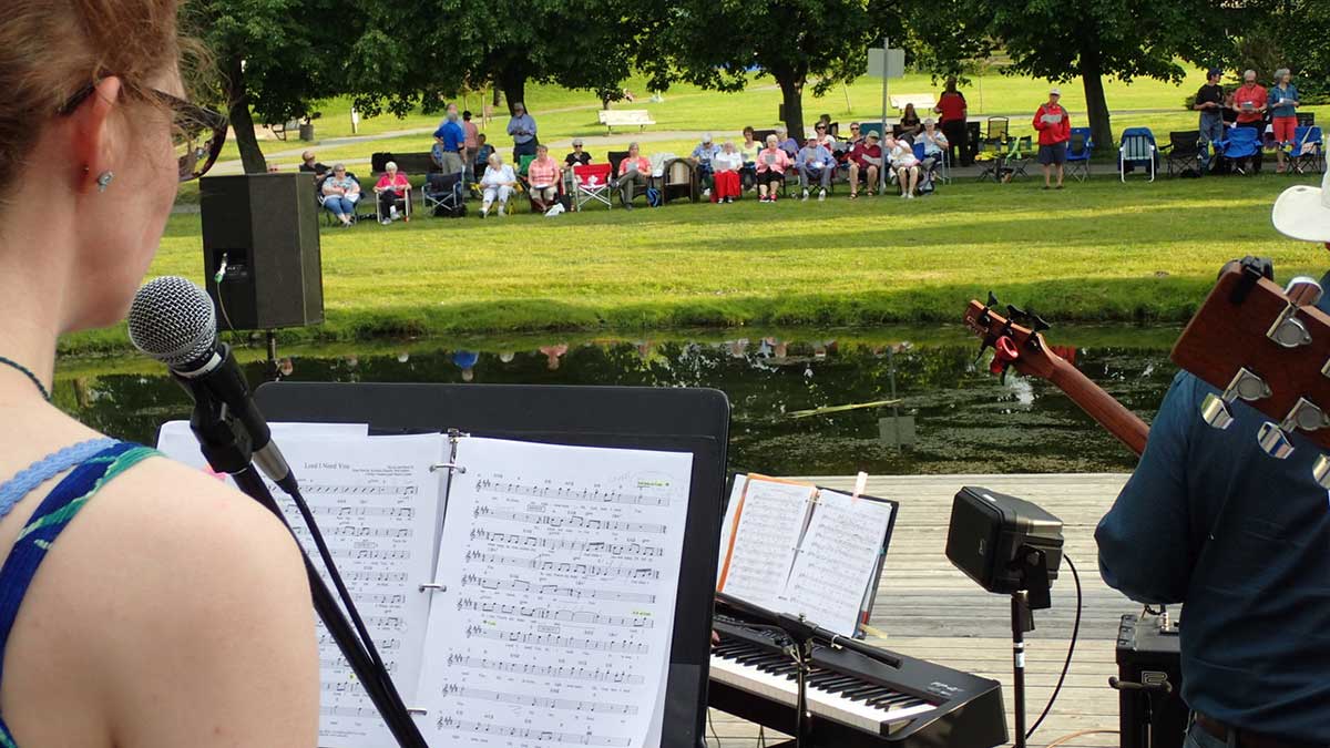 Woman in a park reading sheet music and singing