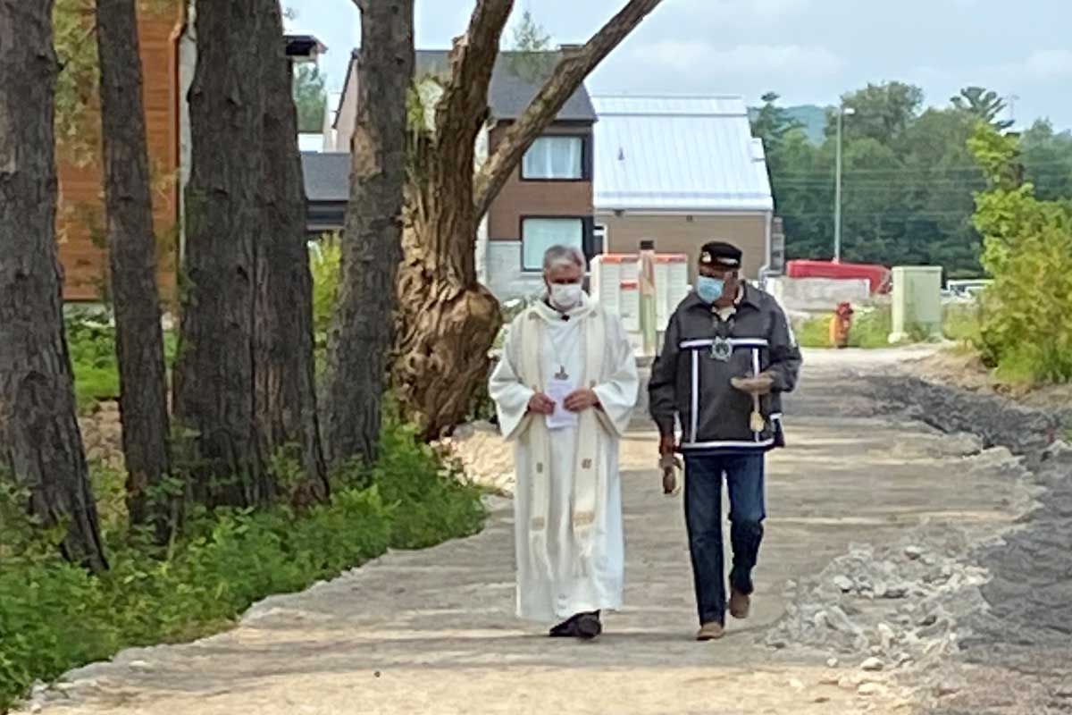 Bishop Shane and Albert Dumont walking on a path under a tree canopy