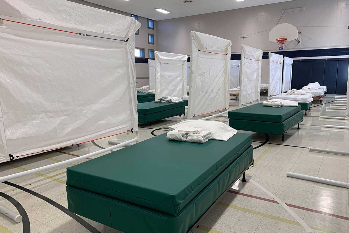 Beds in a gymnasium with fabric dividers