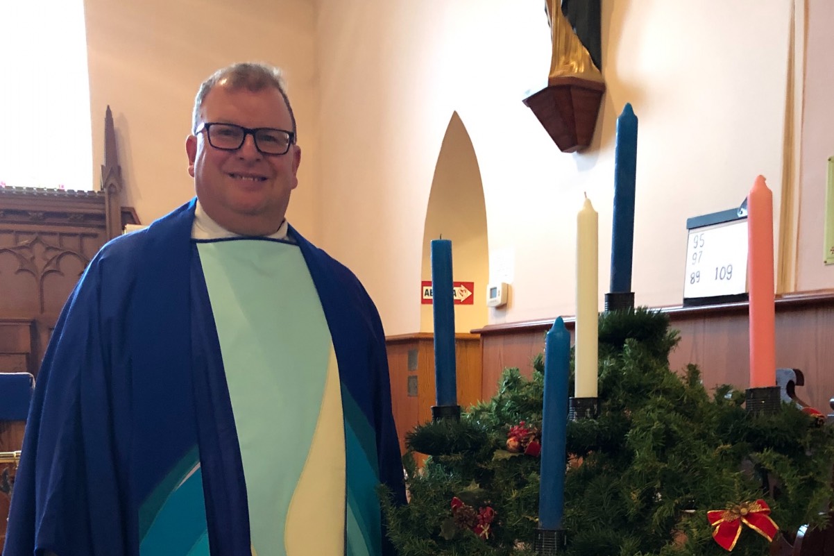 The Rev. Canon Baxter Park standing by Advent candles
