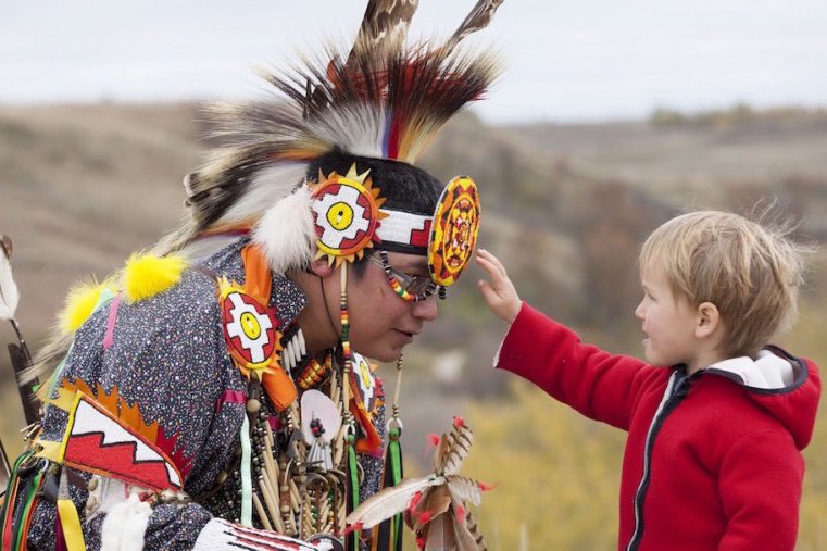 Pow wow dancer talking with a curious child.