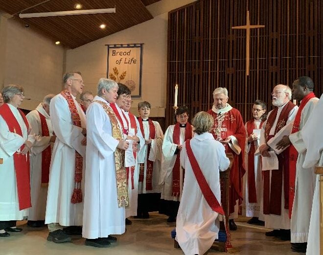 Clergy surround and pray for the Rev. Karen McBride