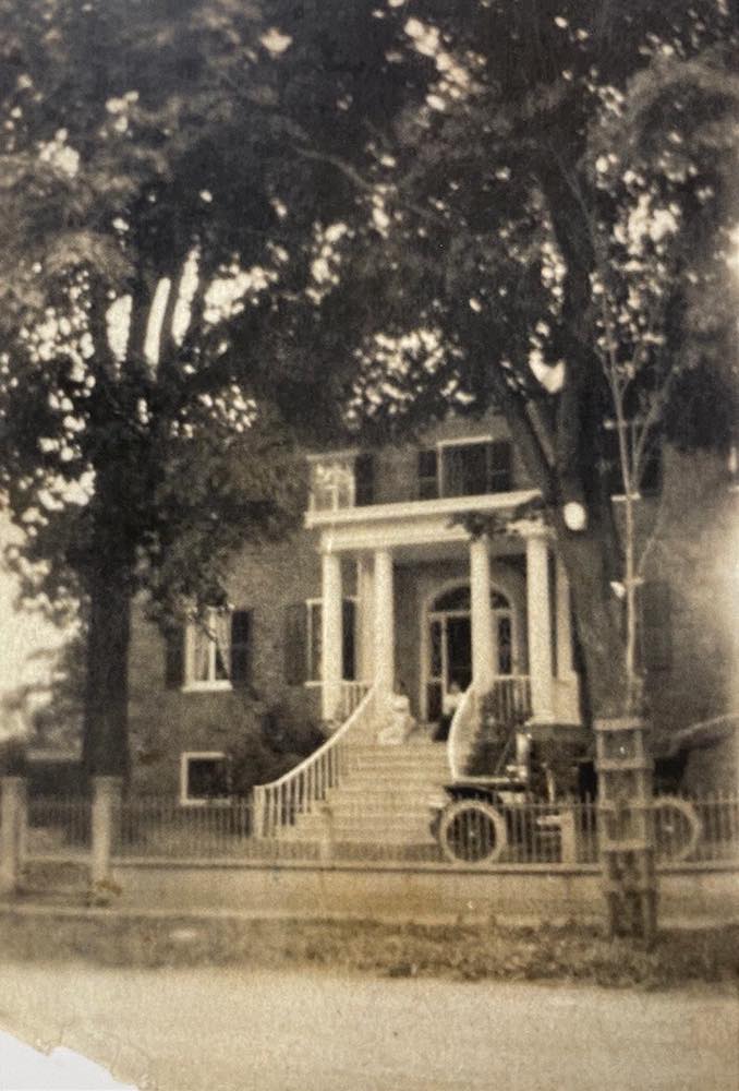 Black and white photo of the entrance to a grand house.