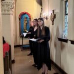 Choir members sing their first number from the side aisles of St. Barnabas.