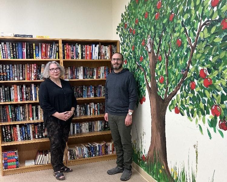 Nora Waddell and Archdeacon Patrick Stephens in the library with apple tree mural.