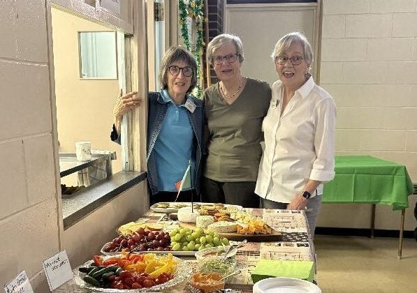 Three women displaying the lunch buffet.