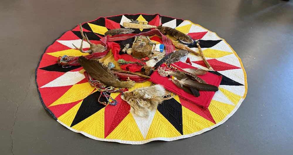 Sacred items on a red, black, white and yellow quiilt