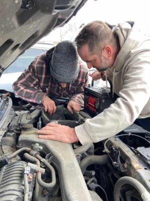 Carl Laliberté helps out with a car battery.