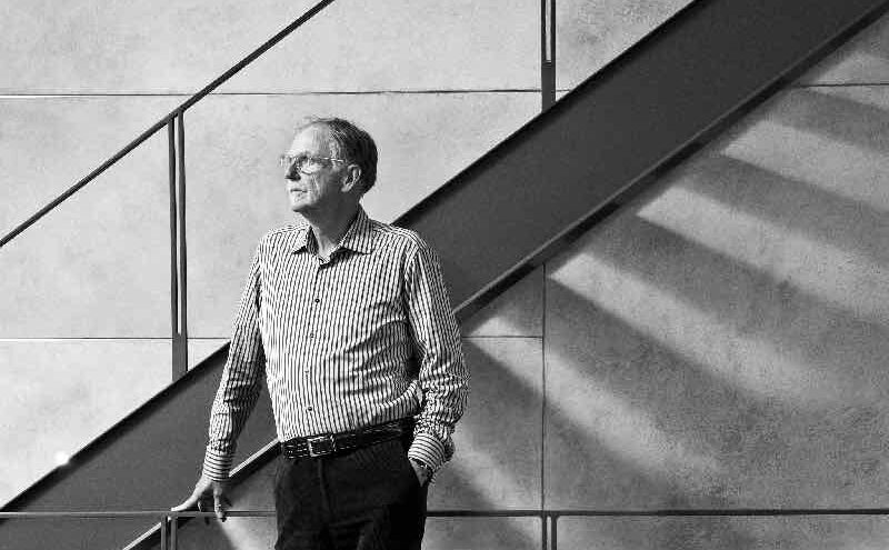Architect Barry Hobin stands by a staircase (black and white photo)