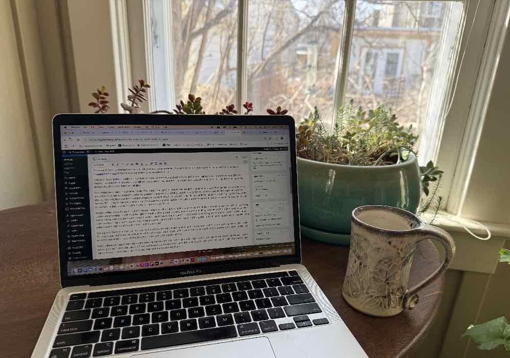 laptop and coffee cup on a table by a window