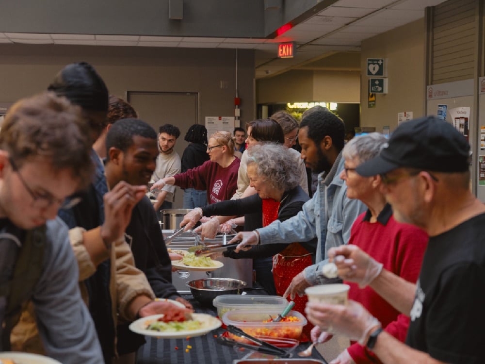 Volunteers dish out meals to students in an atrium at the University of Ottawa. Photo: Contributed