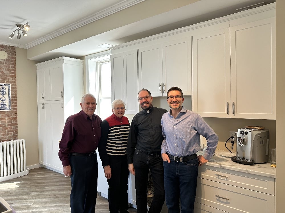 Four people stand in the newly renovated kitchen.