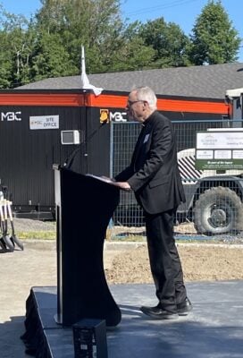 A priest stands at a podium with construction in the background