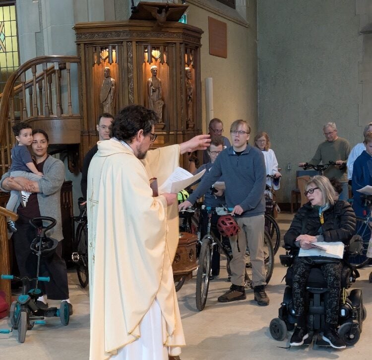 A priest dressed in white robes blesses parishioners' modes of transportation.