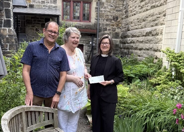 Nicholas Galambos and Judith Dowler present a cheque to the Rev. Victoria Scott in the garden in the Cathedral's beautiful garth.