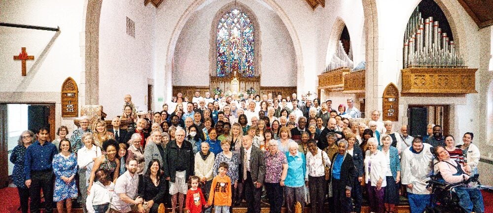 A large crowd of parishioners all pose and smile for the camera at the front of the church