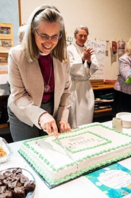 Bishop Kathryn Otley cukes a large anniversary cake.