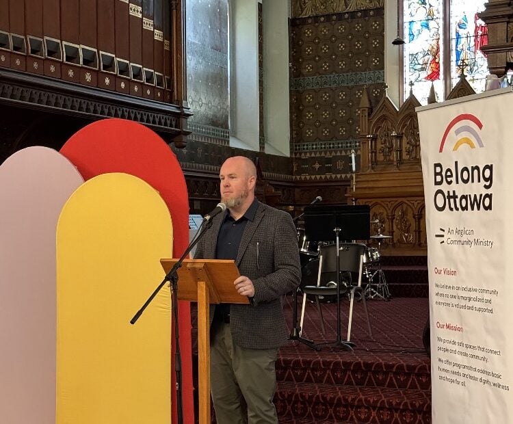 A priest in a suit speaks at the front of St. Albans church