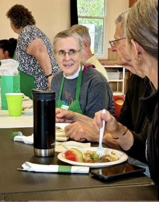 Bishop Kathryn Otley chats with people during the community meal.