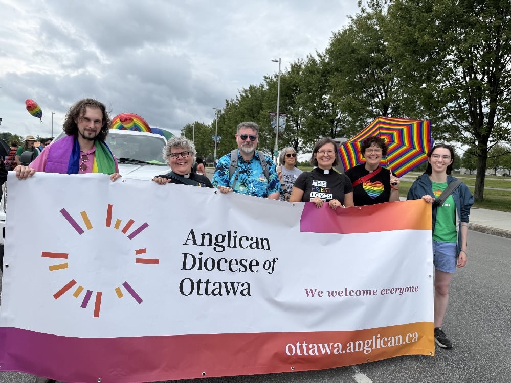Men and women holding a colourful baner for the Anglican Diocese of Ottawa.