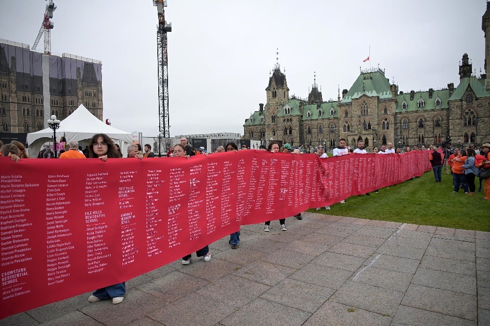 Volunteers on Parliament Hill hold up 60-metre banner with the names of 4,000 Indigenous children who did. not return from residential schools.