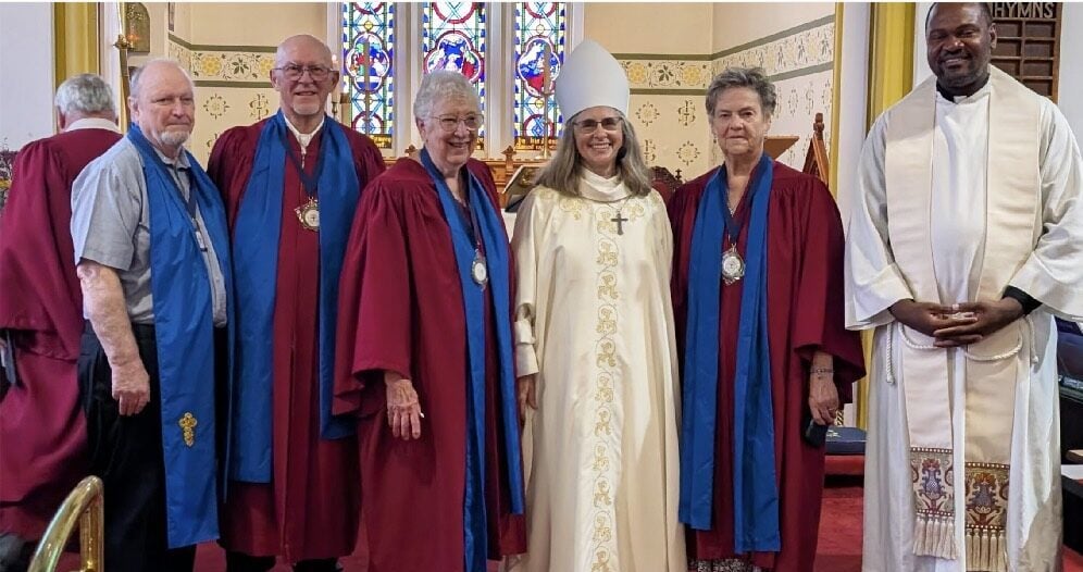 Licensed lay readers wearing medallions pose with Bishop Kathryn Otley an the Rev. Felix Longdon.