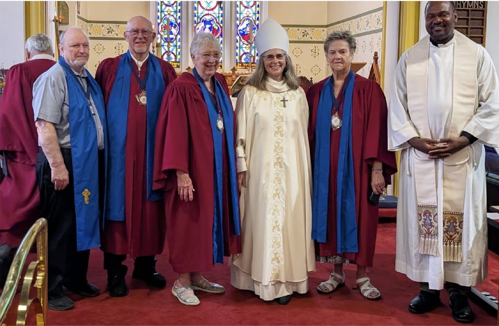 Licensed lay readers wearing medallions pose with Bishop Kathryn Otley an the Rev. Felix Longdon.