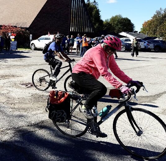 Two cyclists starting off on their route with St. Aidan's church in the background.