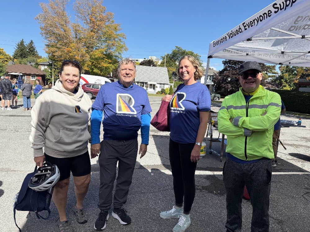 Four people from the St. Bart's team stand in the sunshine ready to ride their bikes.