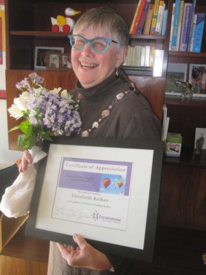 Elizabeth Reicker smiling while holding a certificate