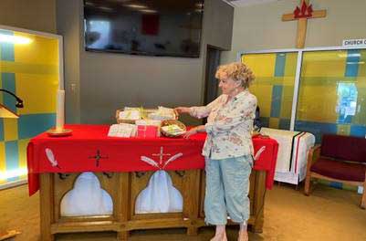 Woman standing in front of an alter covered in red cloth with baskets resting on top